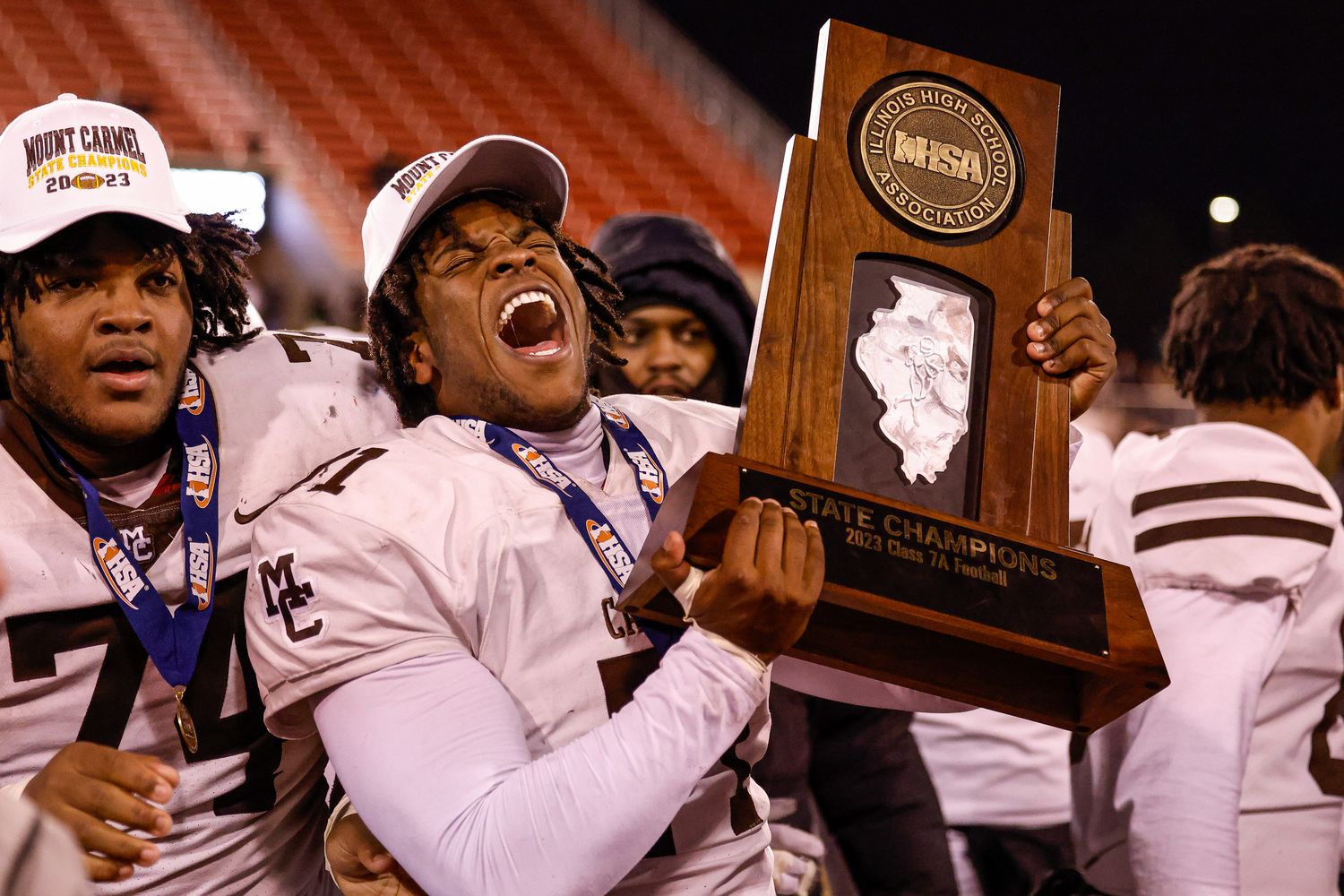 Tavon Rice of Mount Carmel hoists 2023 Illinois 7A football championship trophy